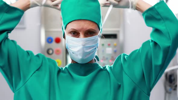 Female nurse tying surgical mask in operation theater alt