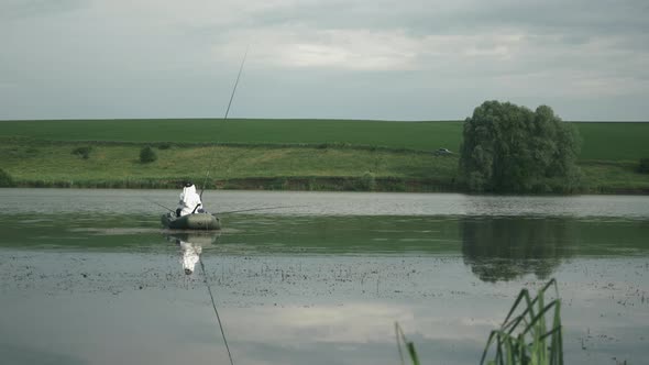 Man in boat fishing with fishing rod. Fisherman catches fish on lake. Fishing on lake. alt