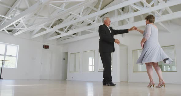 Caucasian senior couple spending time together dancing in a ballroom alt
