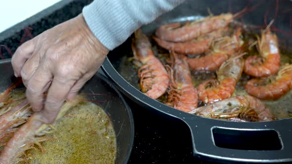 Cook introducing shrimp in a pan with olive oil alt