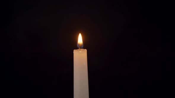 Closeup of an Isolated Burning Candle on a Black Background alt