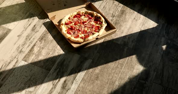 Delivery pizza box. Chopped hot pizza in a cardboard box. Pizza with meat and cheese.