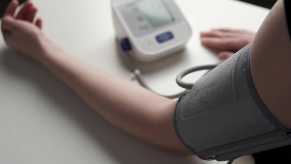 Woman's Hand and Tonometer on White Table for Measuring Blood Pressure