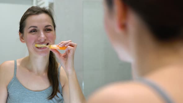 Pretty Woman Brushing Her Teeth in a Bathroom in the Morning alt