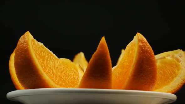 Fresh Orange For Dessert In A White Plate Rotate On A Black Background Close