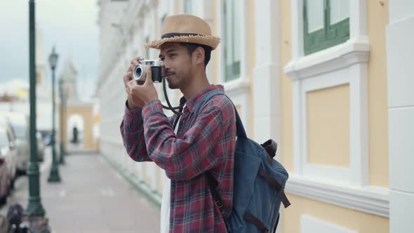 Attractive handsome tourists Asian man using film camera taking a photo.