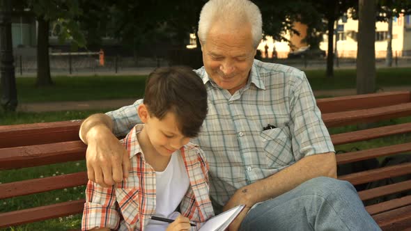 Little Boy Writes in His Notebook What His Grandpa Says alt