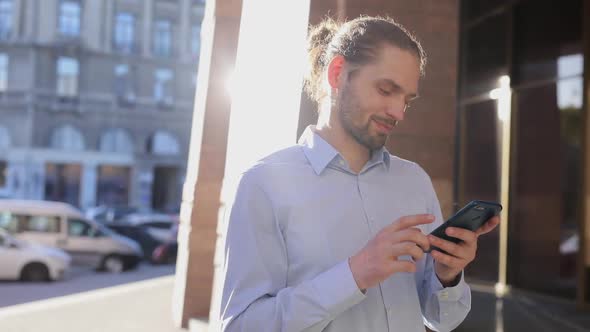 Business Man Using Mobile Phone Outdoors On Sunny Day At Street alt