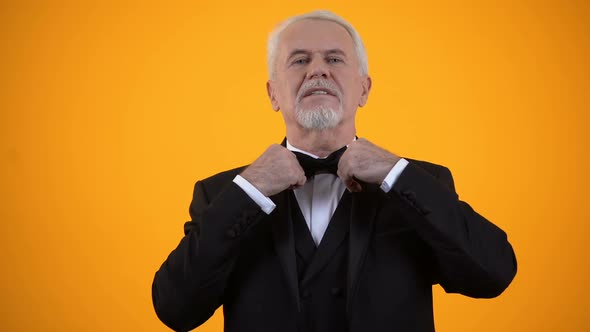 Handsome Elderly Male in Suit Adjusting Bow Tie and Hairstyle, Style and Fashion alt