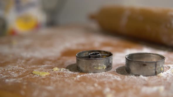 A Close Detail of Cookie Cutters and a Roller on a Table Covered with a Baking Mix. alt