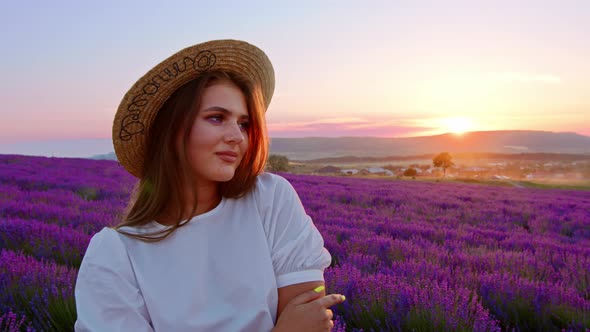 Beautiful Young Woman Wearing White Dress and Hat Standing in a Lavender Field