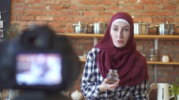 Muslim Woman in Hijab Blogger in the Kitchen in Front of the Camera Talks About Cooking alt