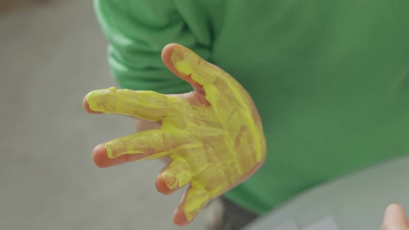 Painting with Yellow and Blue Paint on Kid Hands