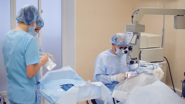 Male Doctor and Two Nurses Are in a Surgery During Operation alt