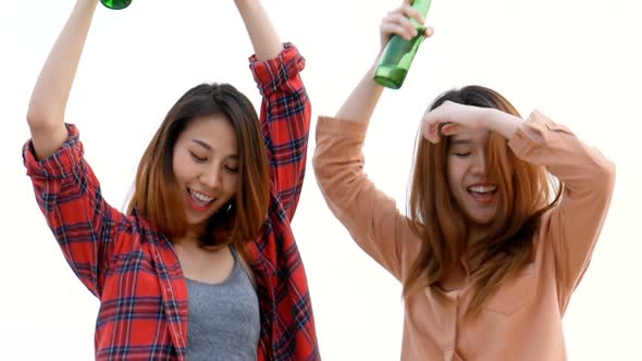 Young Asian woman lesbian couple dancing and clinking bottles of beer party on the rooftop.