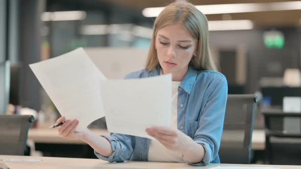 Young Woman Reading Documents in Office alt