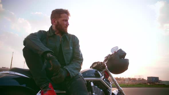 Young Man Sitting on Motorcycle on the Road at Sunset Slow Motion