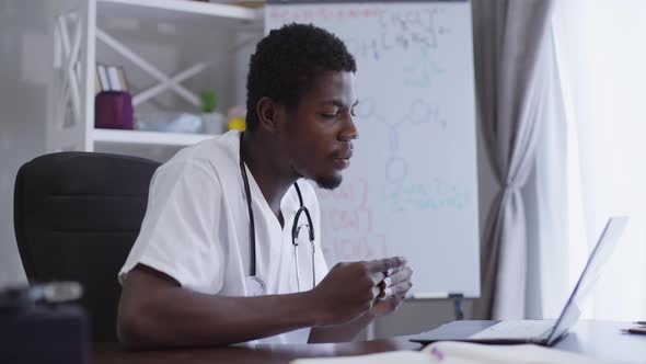 Side View Confident African American Scientist Conferencing Online Sitting at Table with Laptop with alt