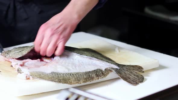 Turning, cleaning and cutting a turbot fish into filets at a Spanish restaurant's kitchen counter alt