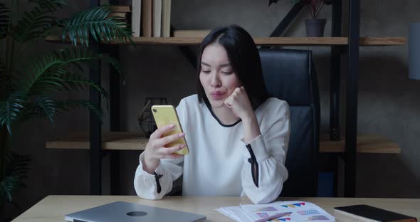 Smiling Relaxed Asian Millennial Woman Hold Smartphone Watching Social Media Stories Video Sit on alt