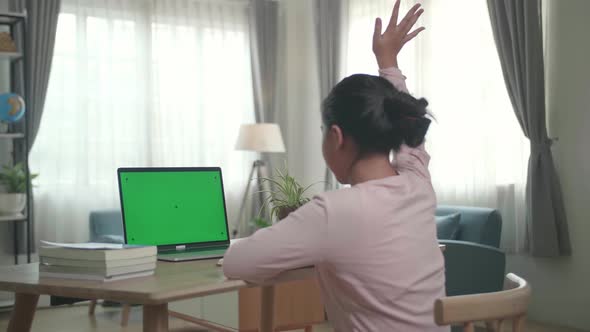 Teenage Girl Sitting At Her Desk Learning Online On A Laptop With Green Mock-Up alt