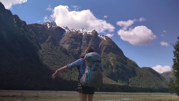 Slider, female hiker stretches in mountainous valley, Routeburn Track New Zealand alt