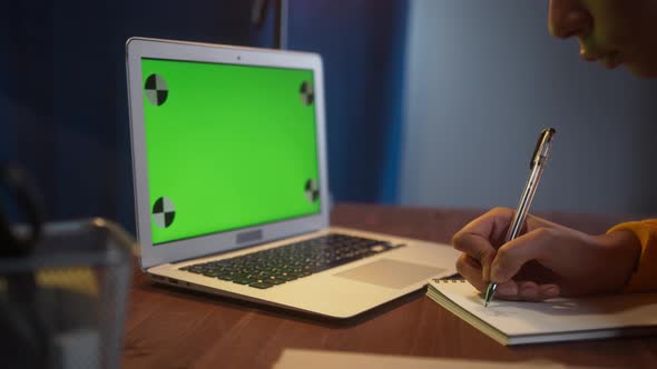 Beautiful Black Woman Sitting at Her Desk Works on a Laptop with Green Chroma Key Mockup Screen alt