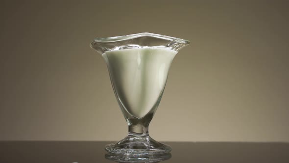 Pouring milk or yogurt into the transparent glass alt