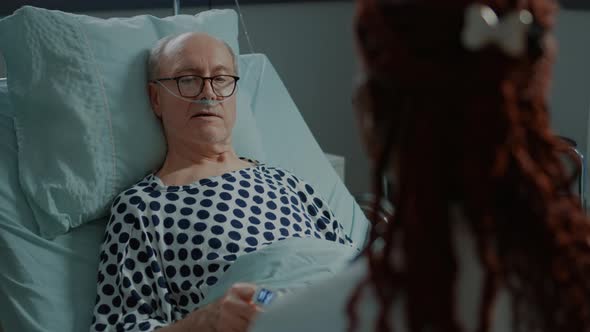 Sick Elder Patient Talking to African American Doctor in Hospital Ward alt