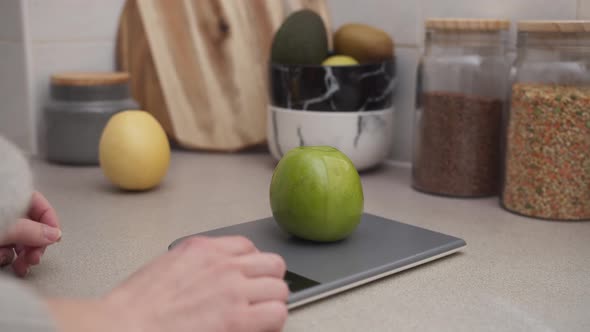 Hands put some fruits on the kitchen scale to weigh Close up shot