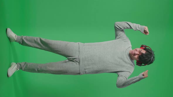 Full Body Of Asian Man Listening To Music With Headphones And Dancing In The Green Screen Studio alt
