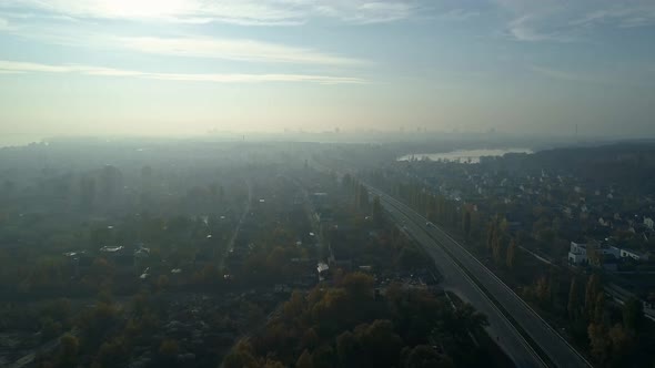 Aerial Drone Footage. Fly Over Autobahn Near Downtown with City on Horizon in Light Fog.