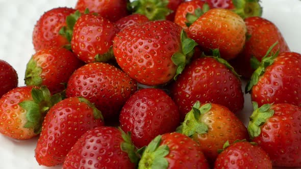 4K Beautiful ripe red strawberry rotates on a plate. Slow rotation of strawberries close-up top view