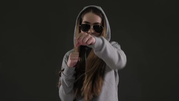 a girl dressed in a tracksuit is engaged in boxing, training on a boxing bag