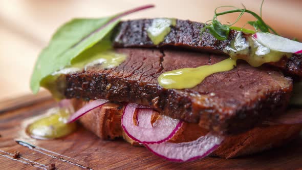 Sandwich with beef meat chunk served on rustic wooden plate in bar alt
