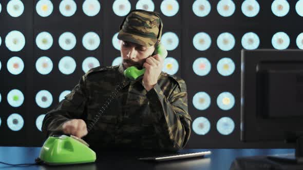 Man in Military Clothes Types on Keyboard Dials Number on Old Telephone Leaves