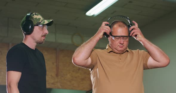 The Trainee Puts on Protective Glasses and Earphones Before Taking a Shot Under the Supervision of alt