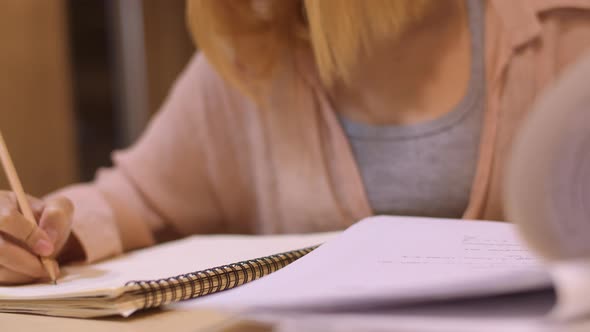 Young undergraduate girl do homework, read textbook, study hard for knowledge on lecture desk. alt