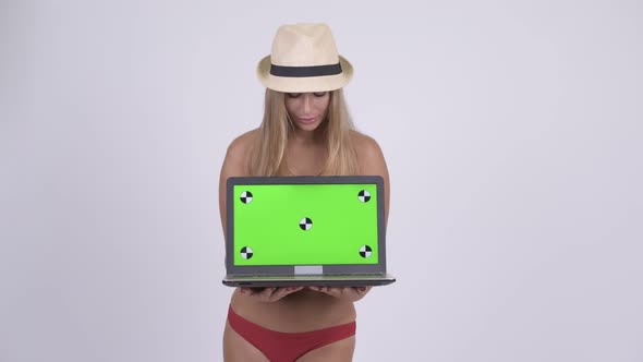 Happy Young Beautiful Blonde Tourist Woman Thinking While Showing Laptop alt