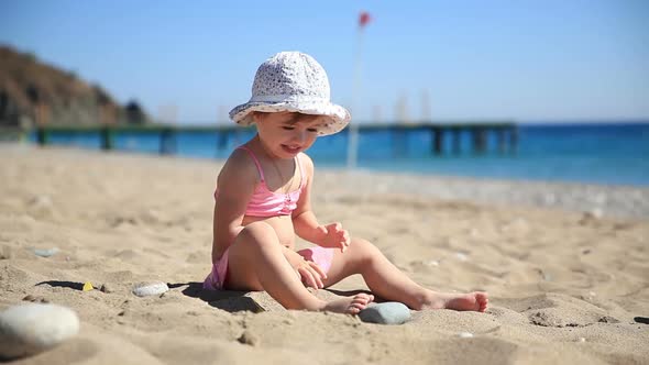 Little Girl in Pink Swimsuit Playing with Sand on the Beach alt