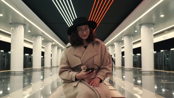 The Girl is Waiting for Her Train in the Subway and Texting on Her Phone