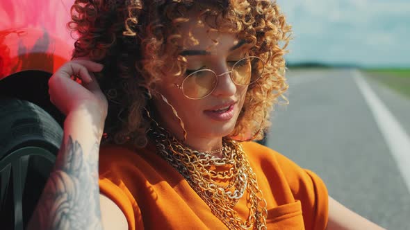 Beautiful Model Woman with Tattoo Is Posing with a Red Car at Summer Landscape alt