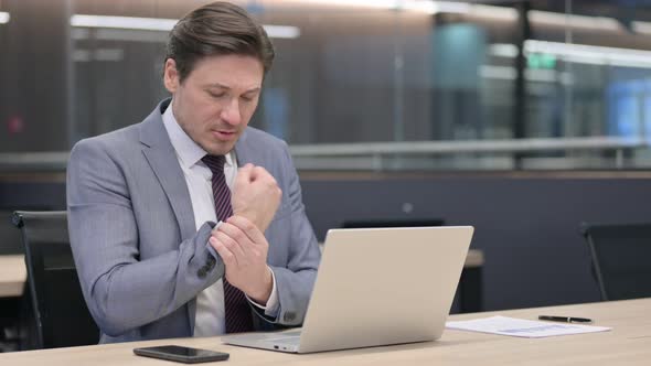 Middle Aged Businessman having Wrist Pain while using Laptop  alt