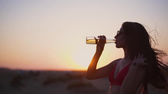 Portrait of Woman Drinking Beer and Looking at Sunset View