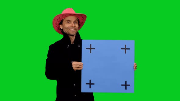 Cheerful Man in Black Coat and Pink Cowboy Hat Speaking and Holding Blank Blue Billboard