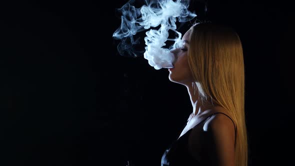 Girl of Extraordinary Beauty Smokes an Electronic Cigarette, Black Background, Side Viwe alt