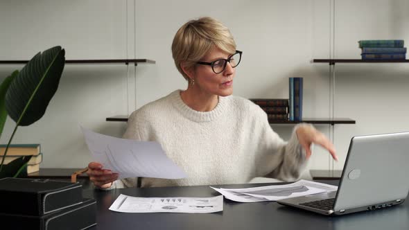 A Middleaged Woman Sitting at a Desk in an Office Working with a Laptop is Overwhelmed and Throws alt