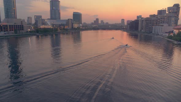 An Aerial View of a Boat That Floats on a River in the City Centre at Sunset alt