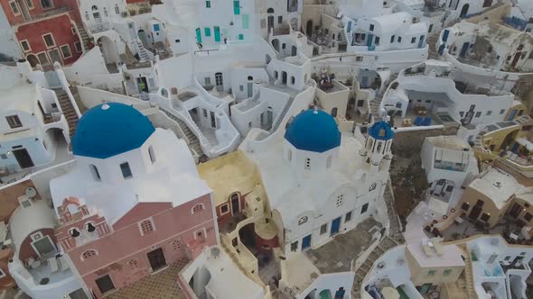 Flying over famous blue domed church in Oia on Santorini Island in Greece alt