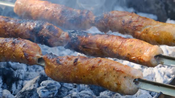 Sausages on Skewers are Cooked on the Portable Grill Outdoor Close Up BBQ alt